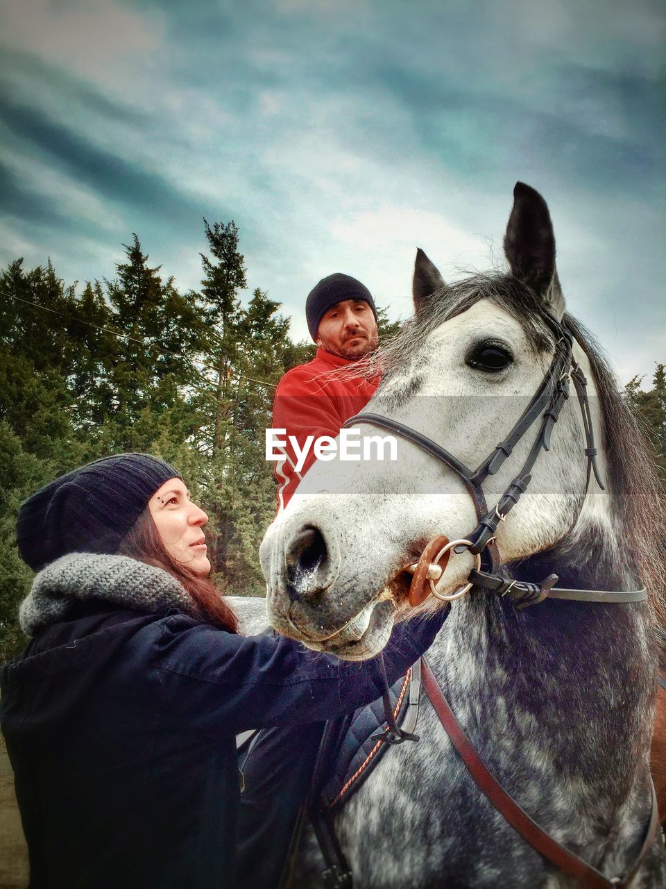 Low angle view of friends with horse against cloudy sky