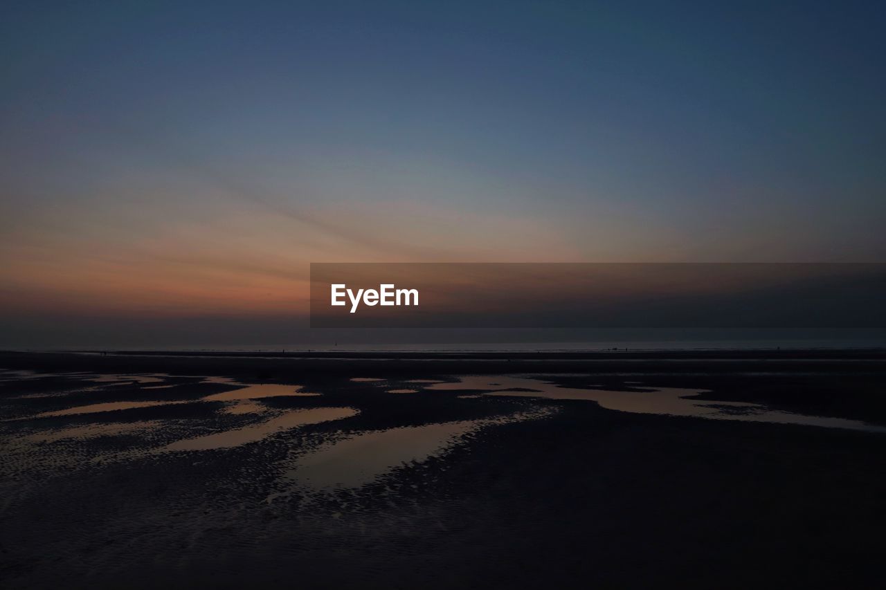 SCENIC VIEW OF BEACH AGAINST SKY AT SUNSET