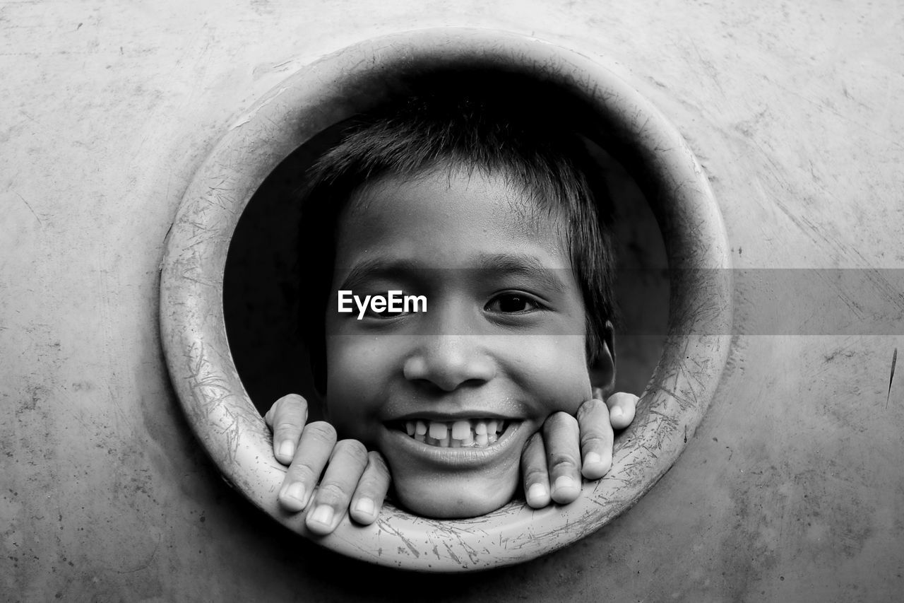 Portrait of smiling boy peeking through hole