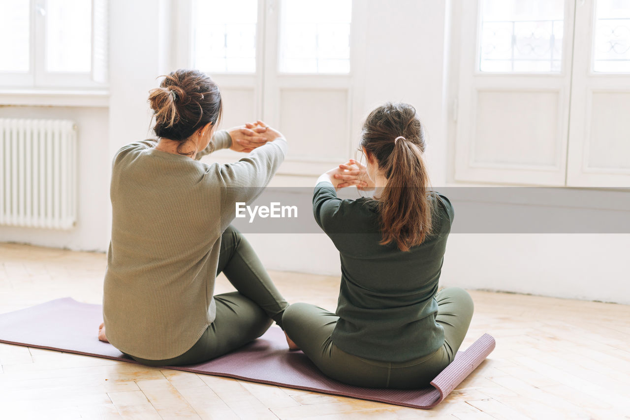 Attractive mother middle age woman and daughter teenager ptactice yoga together in the bright studio