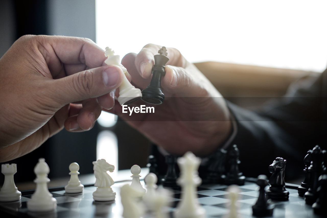 Cropped hands of friends holding chess pieces