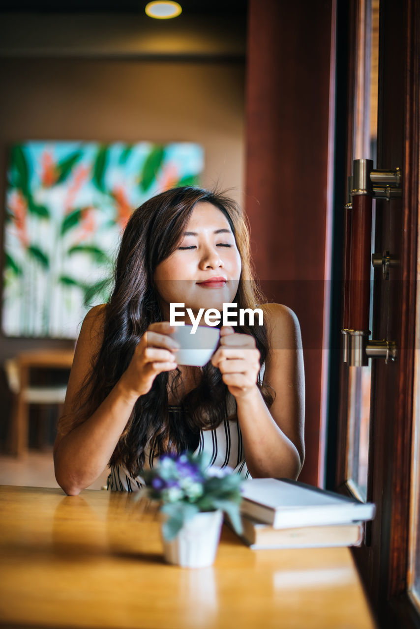 PORTRAIT OF YOUNG WOMAN SITTING AT RESTAURANT