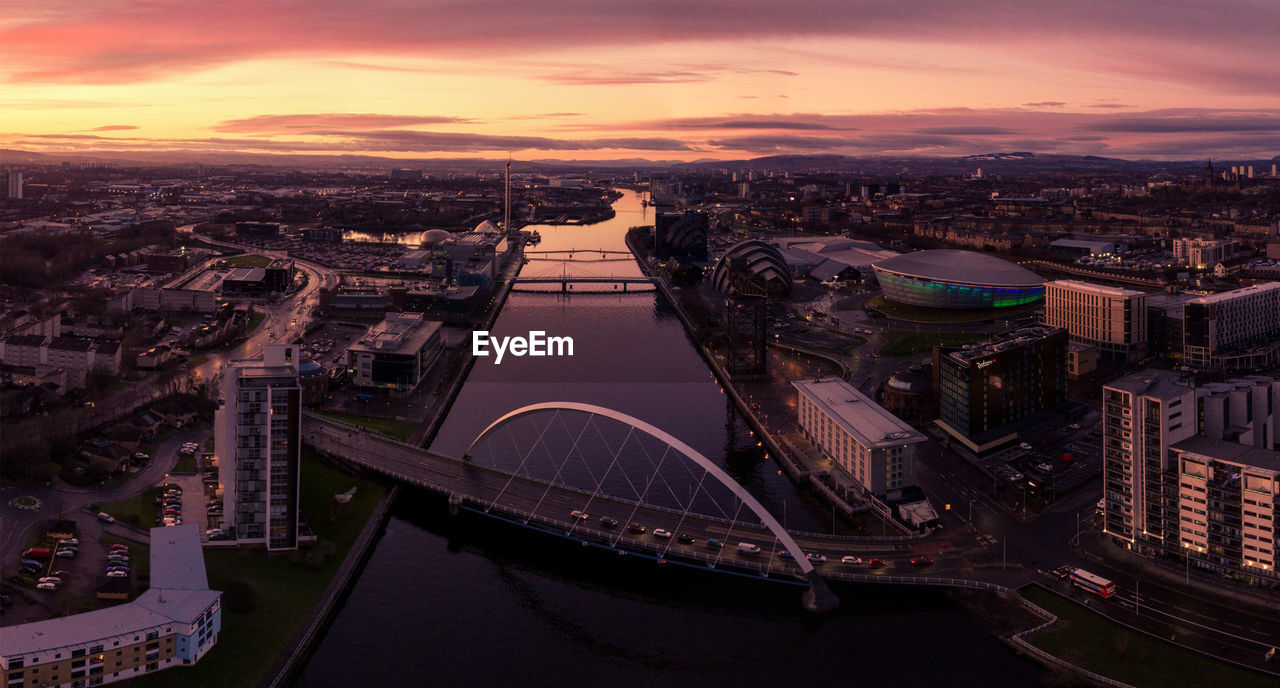 HIGH ANGLE VIEW OF CITY AT WATERFRONT DURING SUNSET