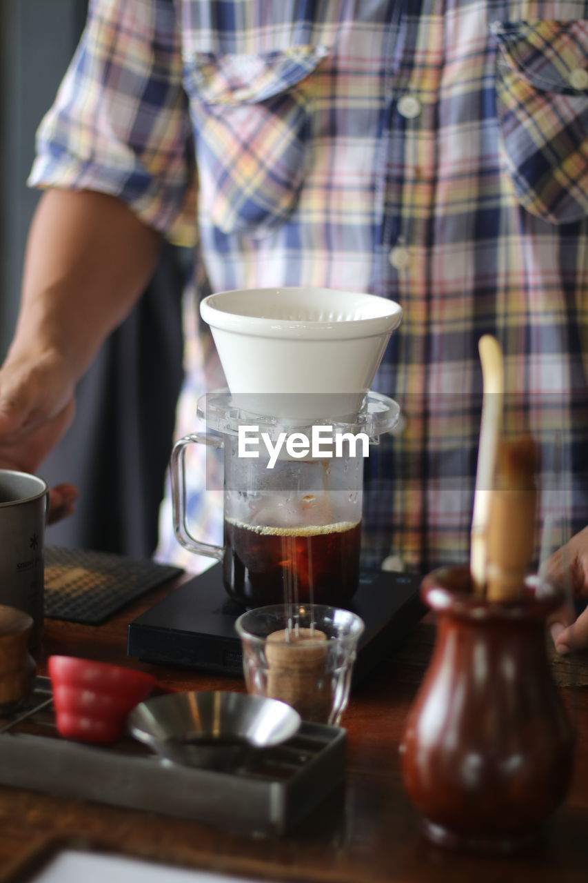 Midsection of man holding coffee in gym