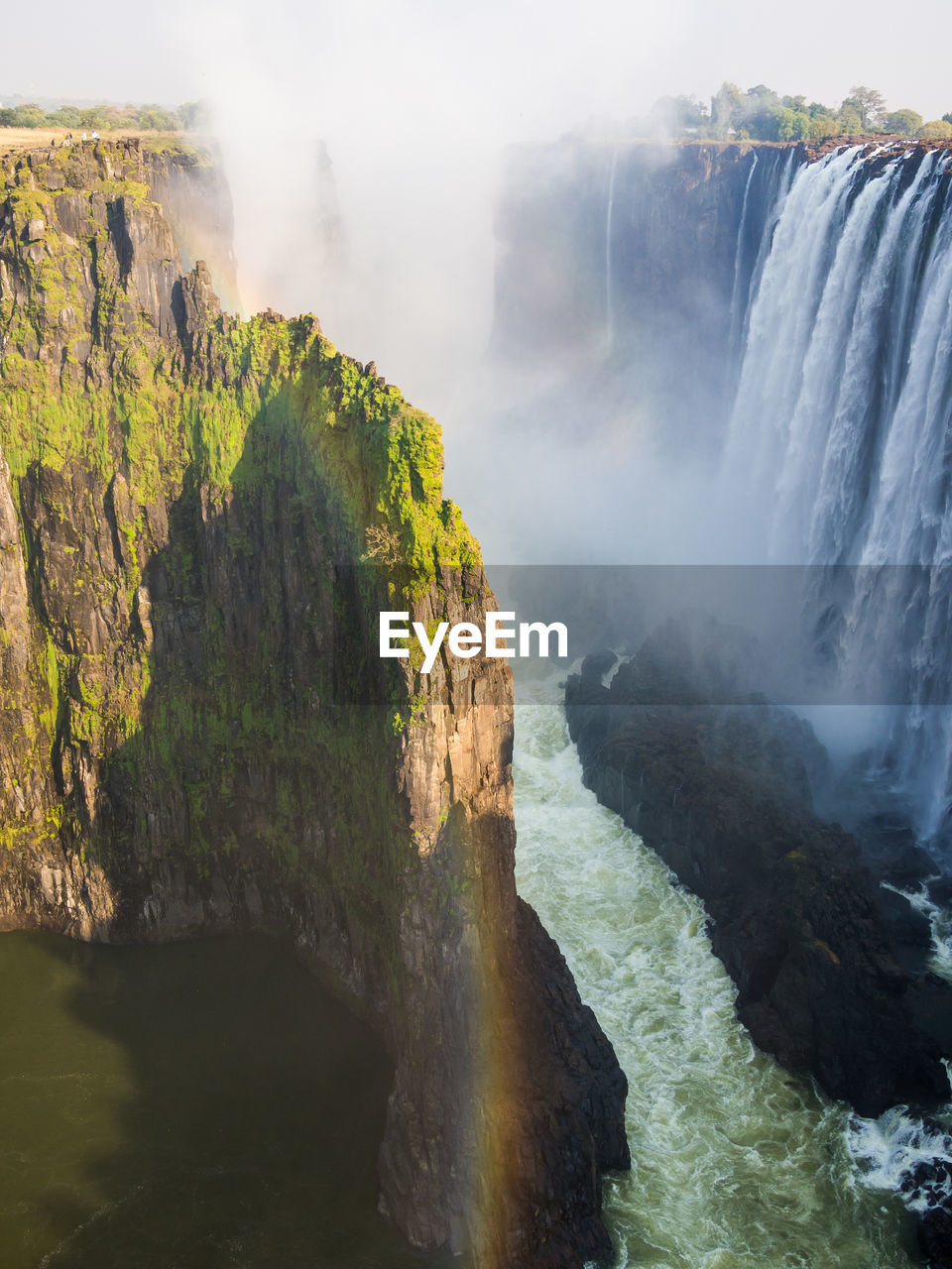 Scenic view of victoria falls waterfall with rainbow at border between zambia and zimbabwe