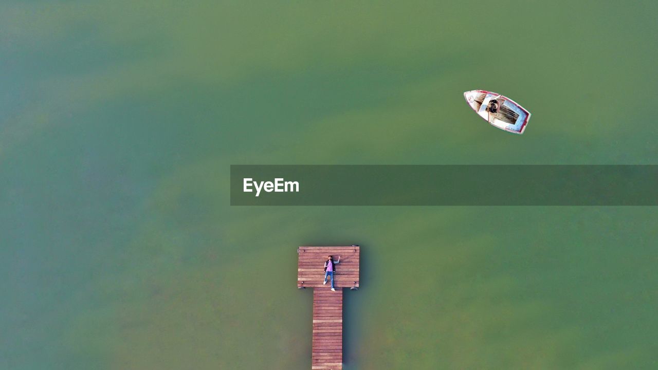 Aerial view of man lying on pier by lake