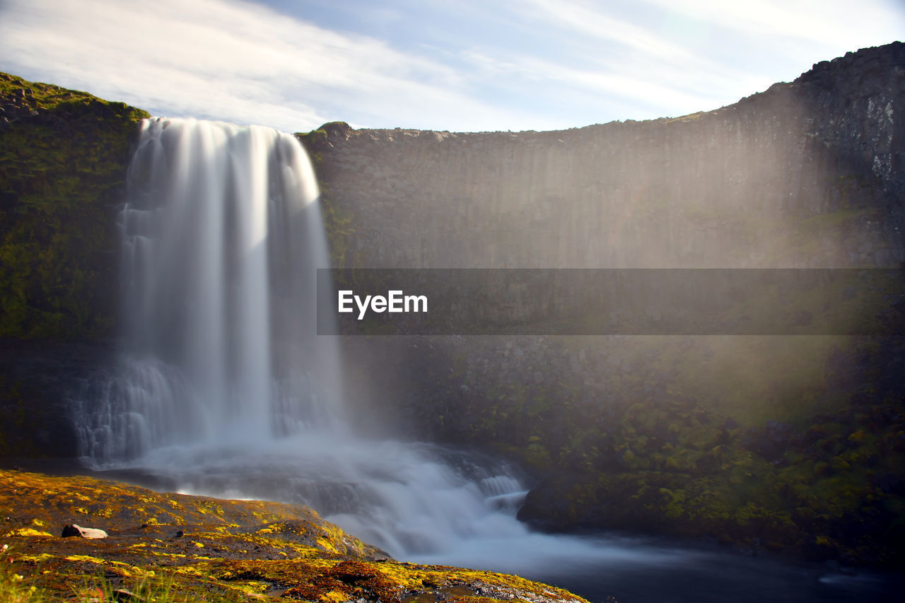 Scenic view of waterfall against sky