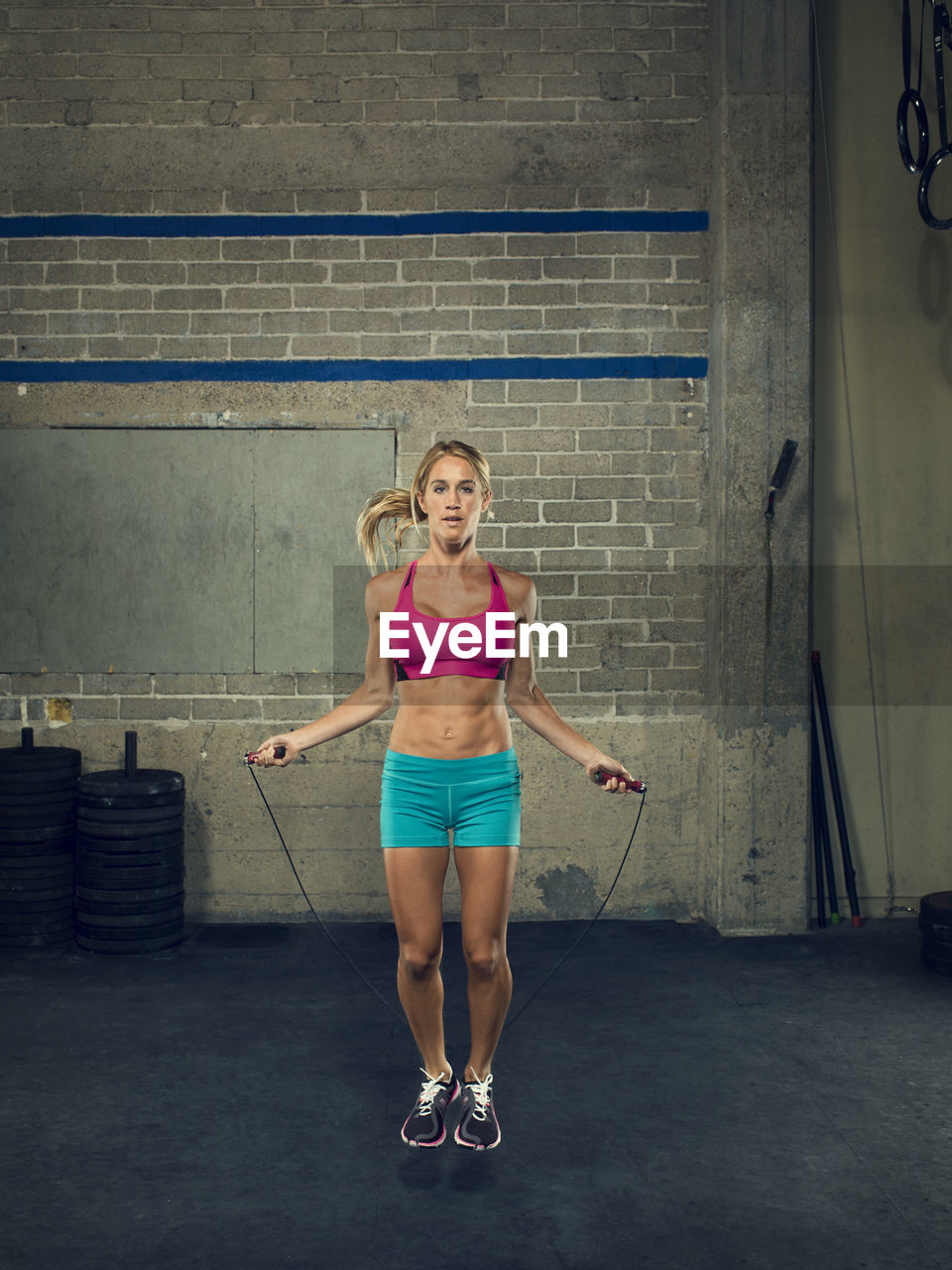 Portrait of confident female athlete skipping at gym