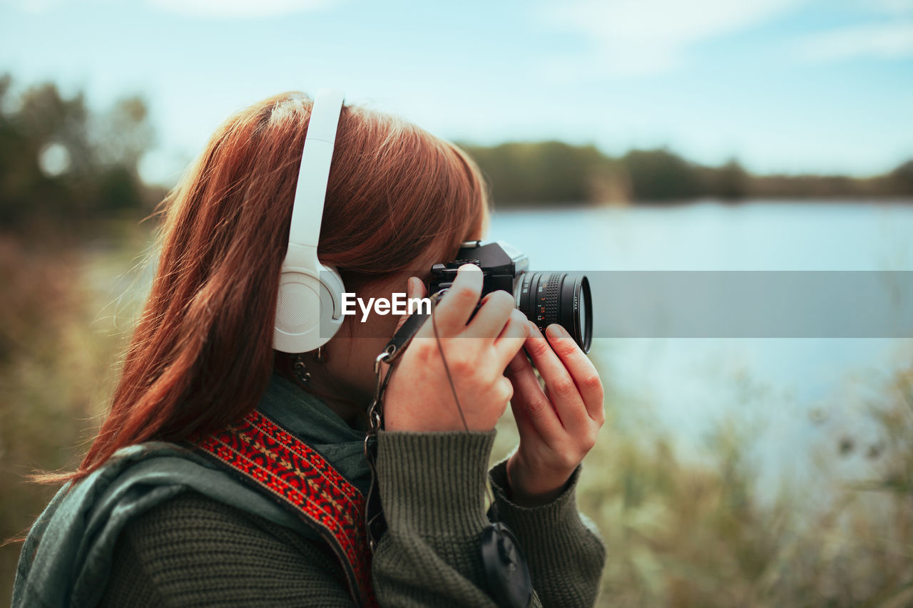 Close-up of young woman photographing by lake