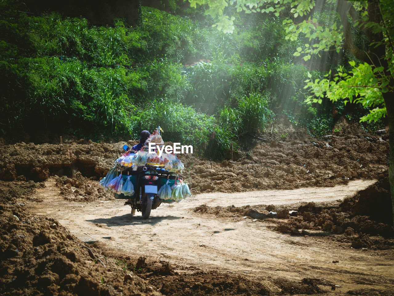 The seller is carrying various sacks of food on motorbike for selling in the countryside.