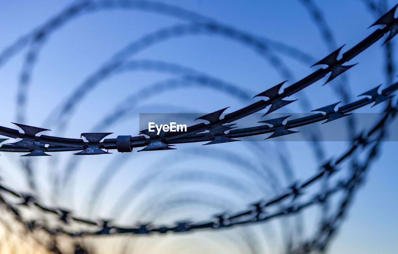 CLOSE-UP OF BARBED WIRE AGAINST SKY