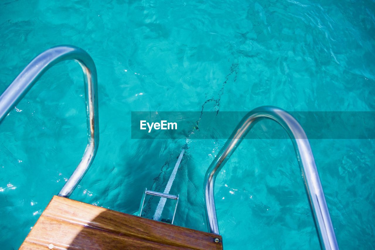 HIGH ANGLE VIEW OF SWIMMING POOL AGAINST BLUE WATER