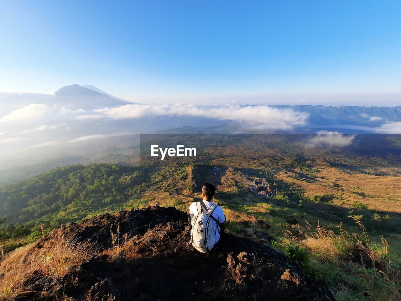 Young man looking at the view from the top of the mountain