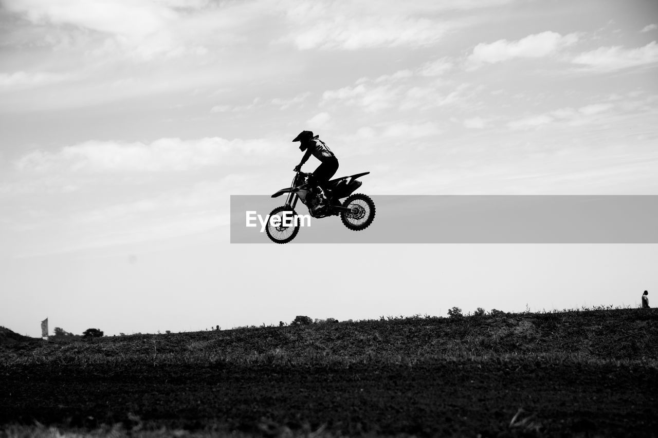 Man riding motorbicycle on field against sky