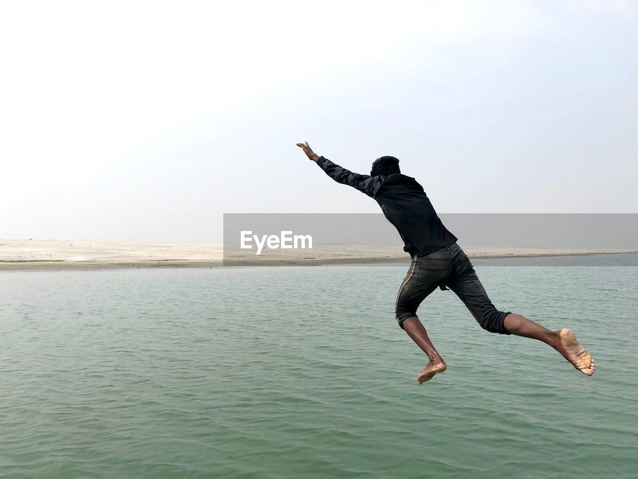 FULL LENGTH OF MAN JUMPING IN SEA