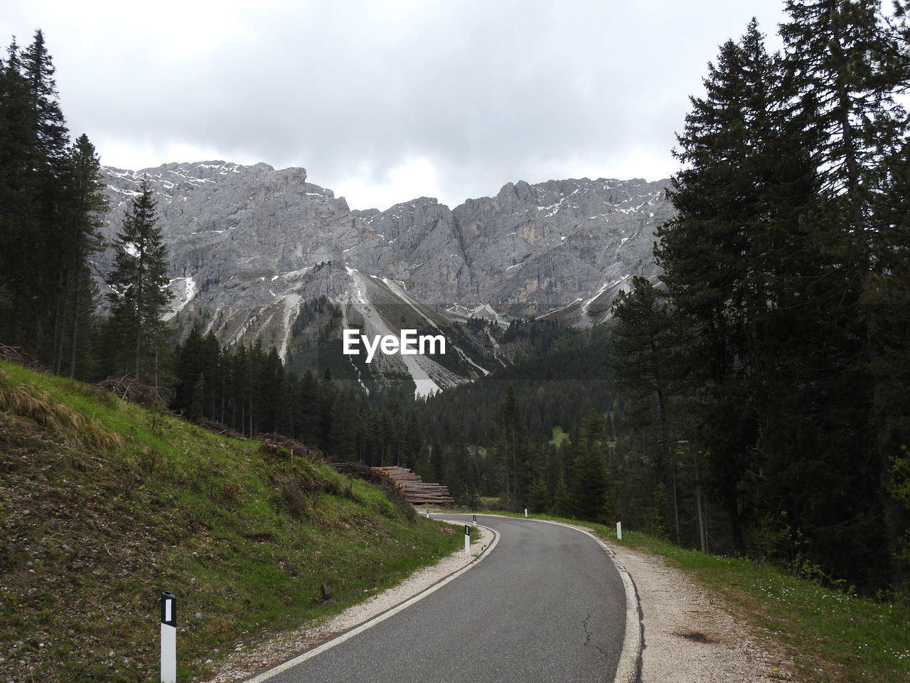 Road amidst trees and mountains against sky