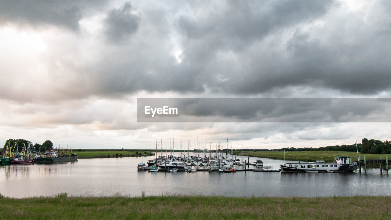 Boats in sea against cloudy sky