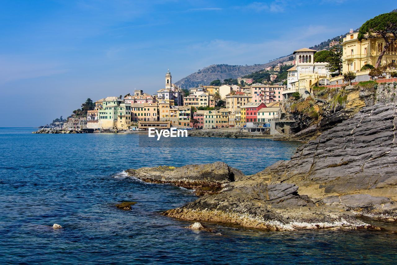 Scenic view of sea by buildings against sky