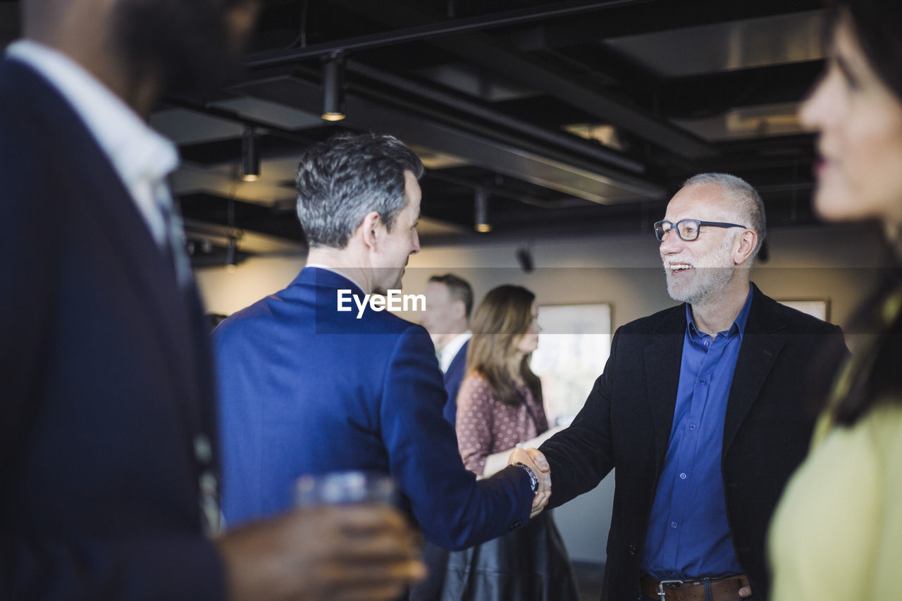 Male entrepreneurs shaking hands while standing in office