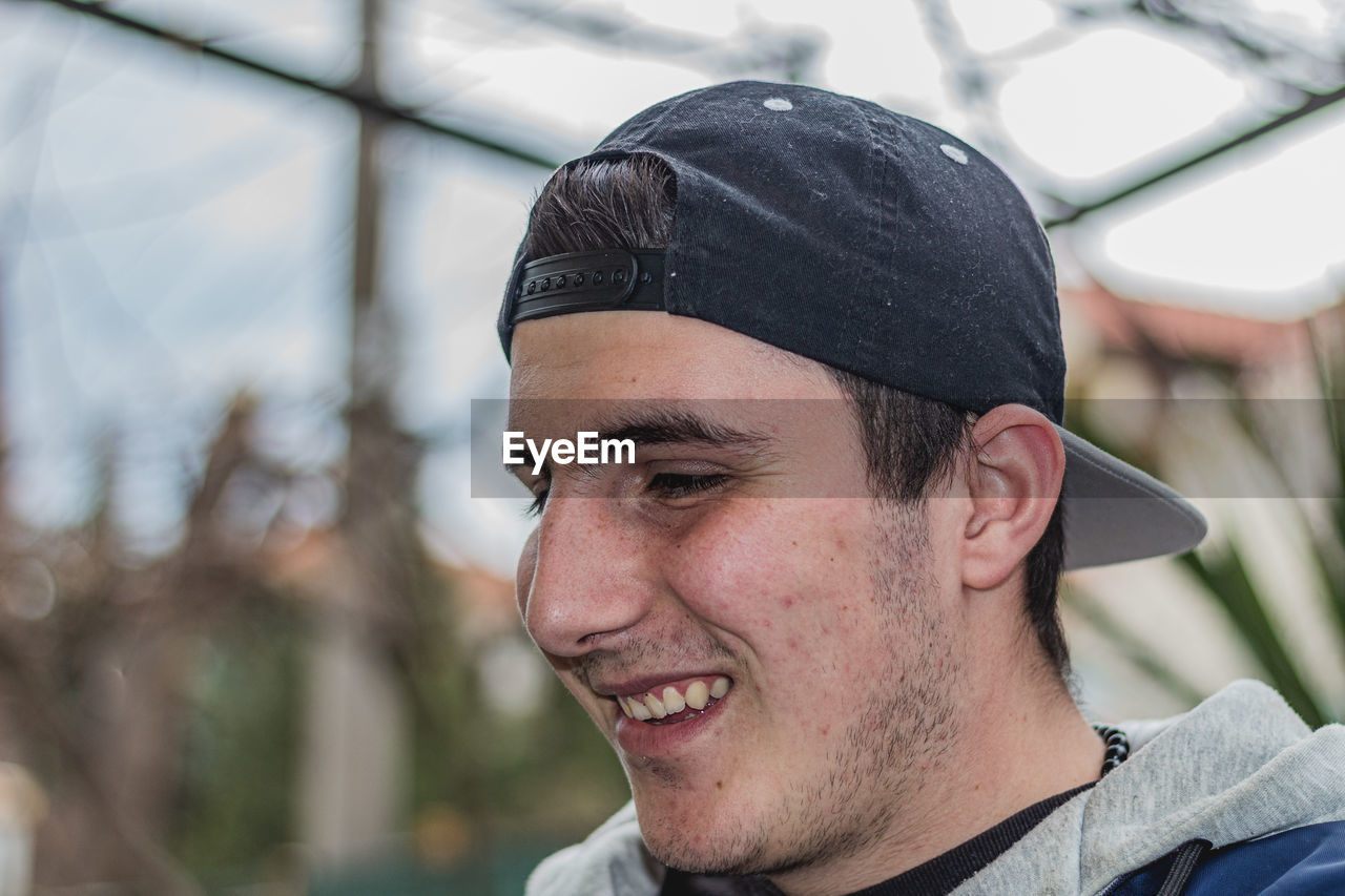 PORTRAIT OF SMILING YOUNG MAN LOOKING AWAY