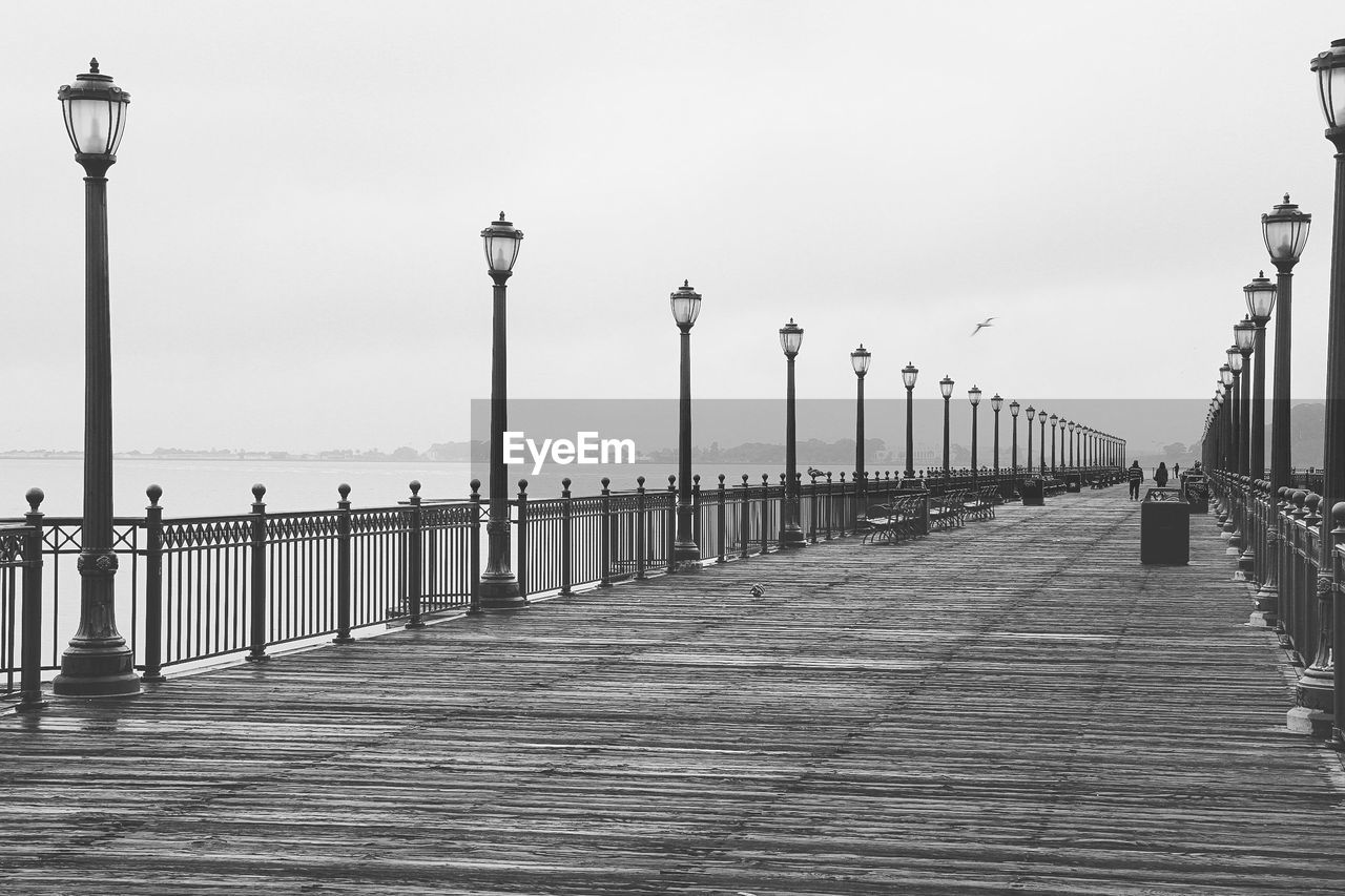 Street lights on pier over sea against clear sky