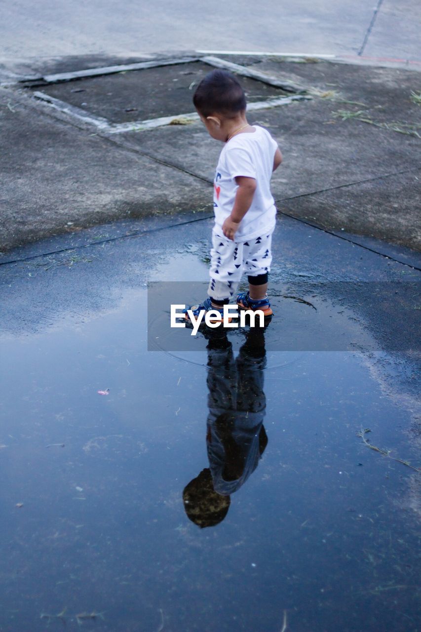 Rear view of child standing in puddle on street