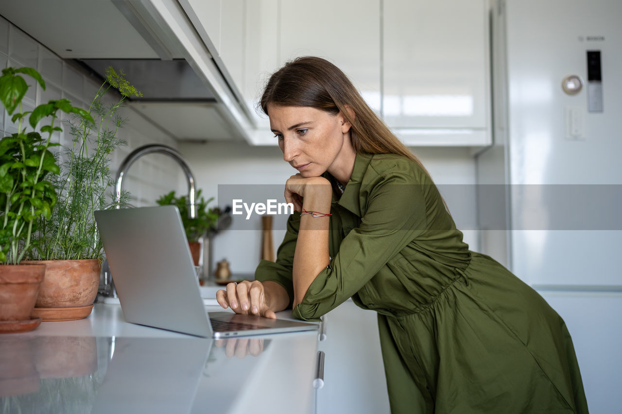 Focused female engrossed in reading of cooking receipts, choosing food, products in online shop