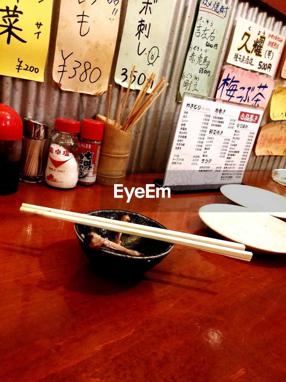 Empty bowl and chopsticks on red table in restaurant