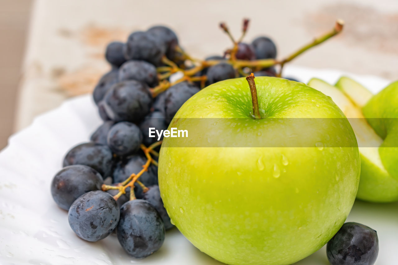 Green apple and black grapes on a fruit plate