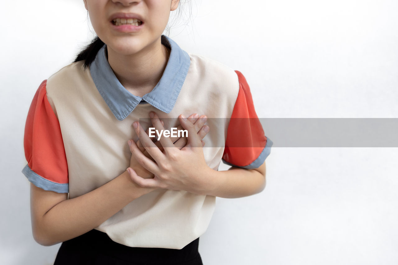 LOW SECTION OF GIRL STANDING AGAINST GRAY BACKGROUND