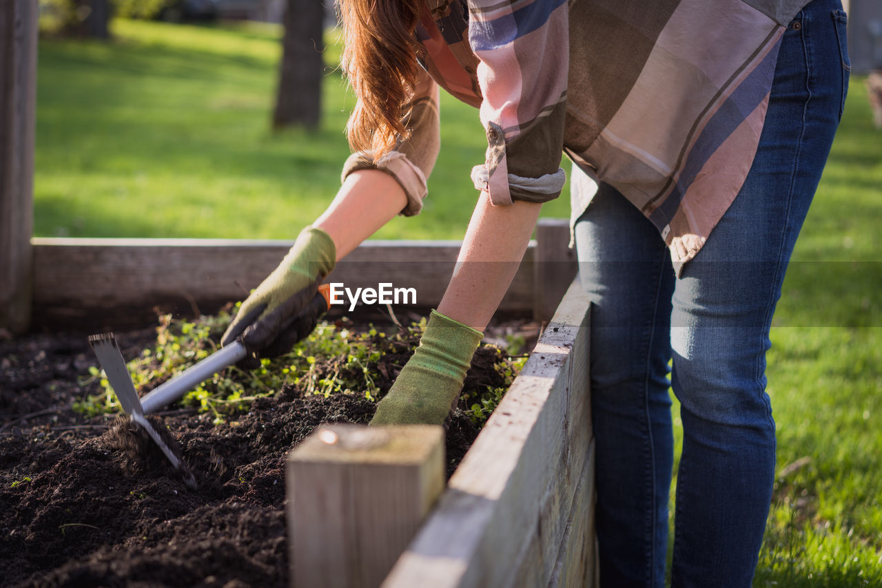 Midsection of woman digging soil