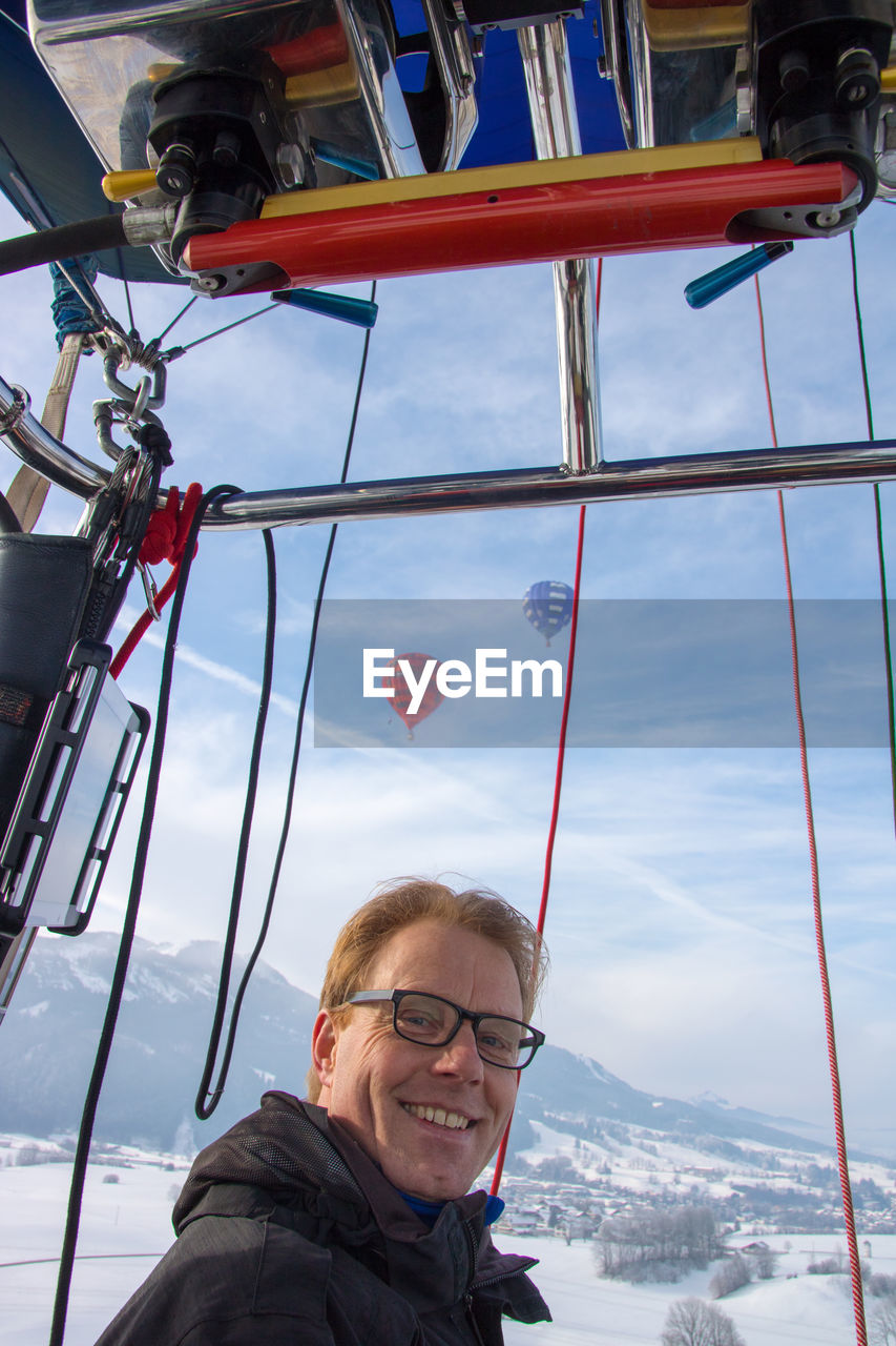 LOW ANGLE PORTRAIT OF HAPPY MAN AGAINST SKY