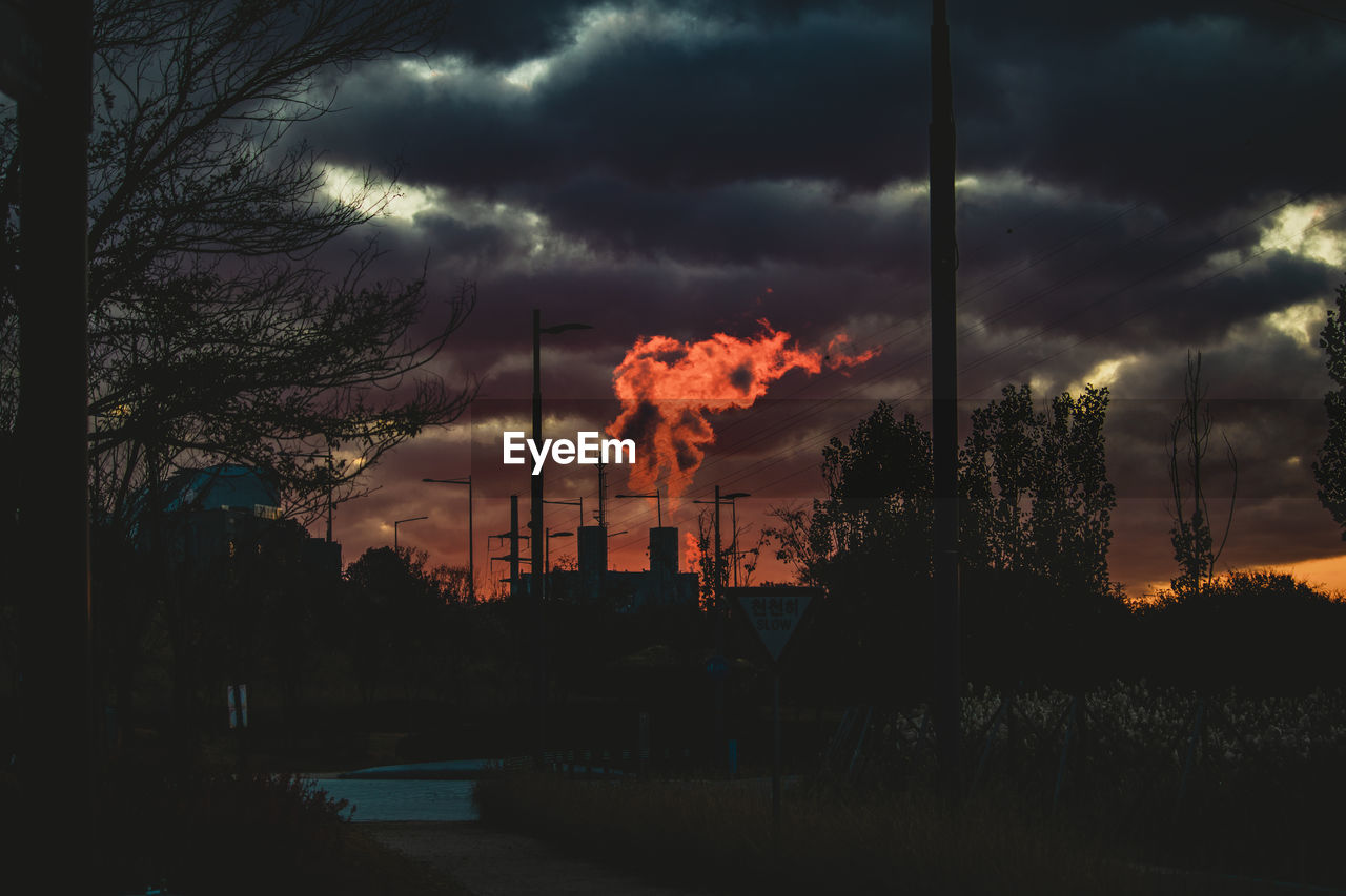 SILHOUETTE SMOKE EMITTING FROM CHIMNEY AGAINST SKY