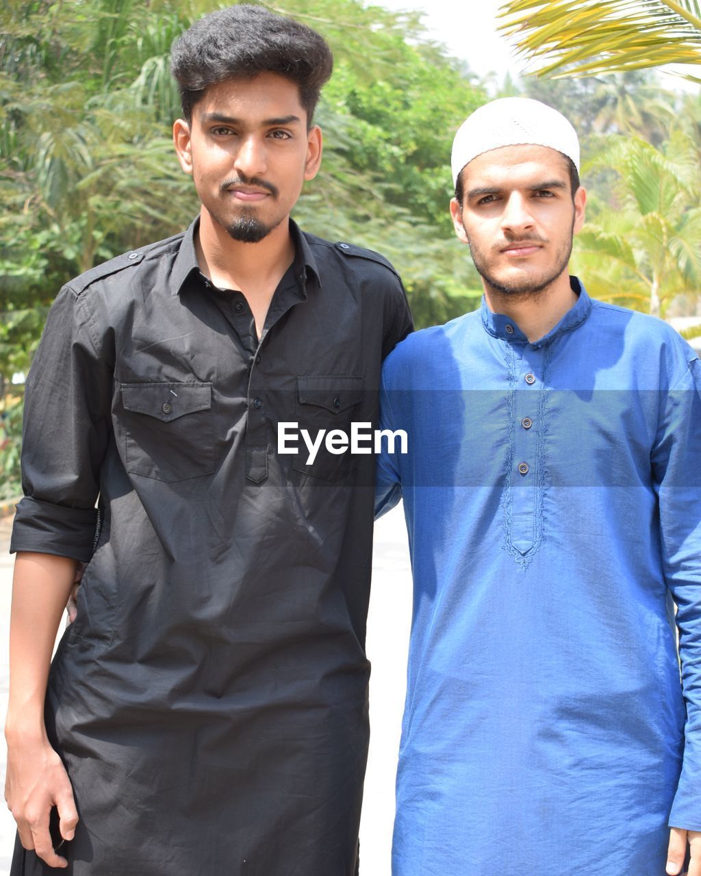 Portrait of friends in traditional clothing standing on road against trees