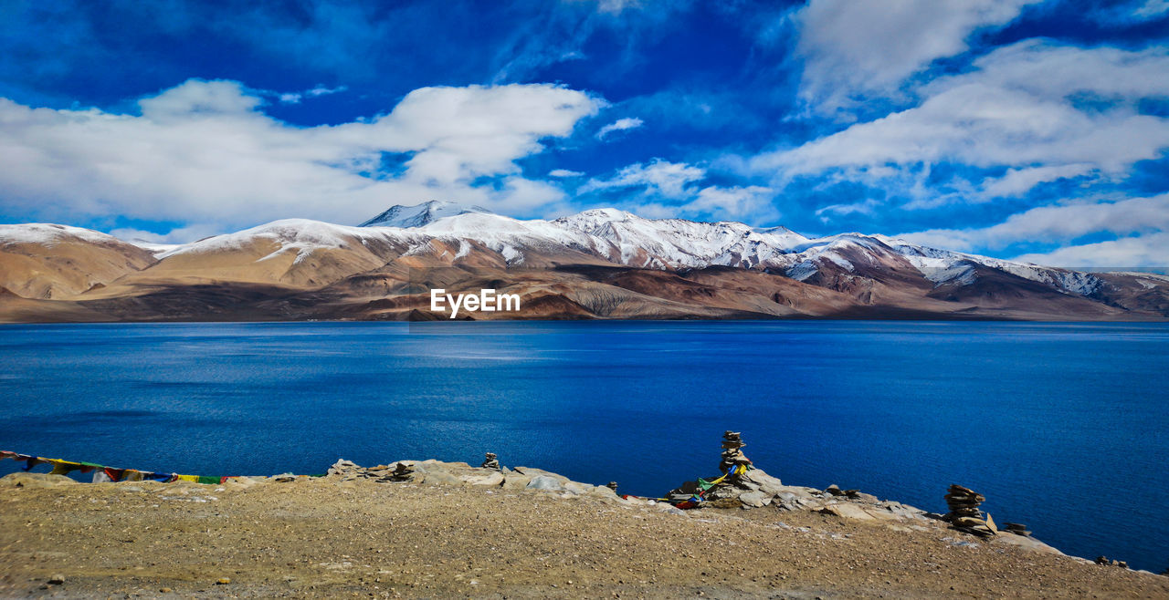 Panoramic view of lake by snowcapped mountains against sky
