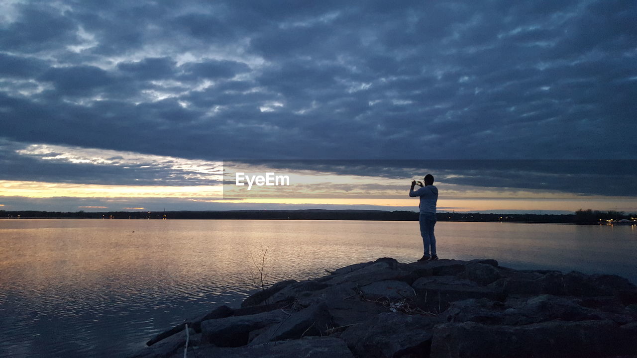 SILHOUETTE WOMAN STANDING ON SHORE AGAINST SKY