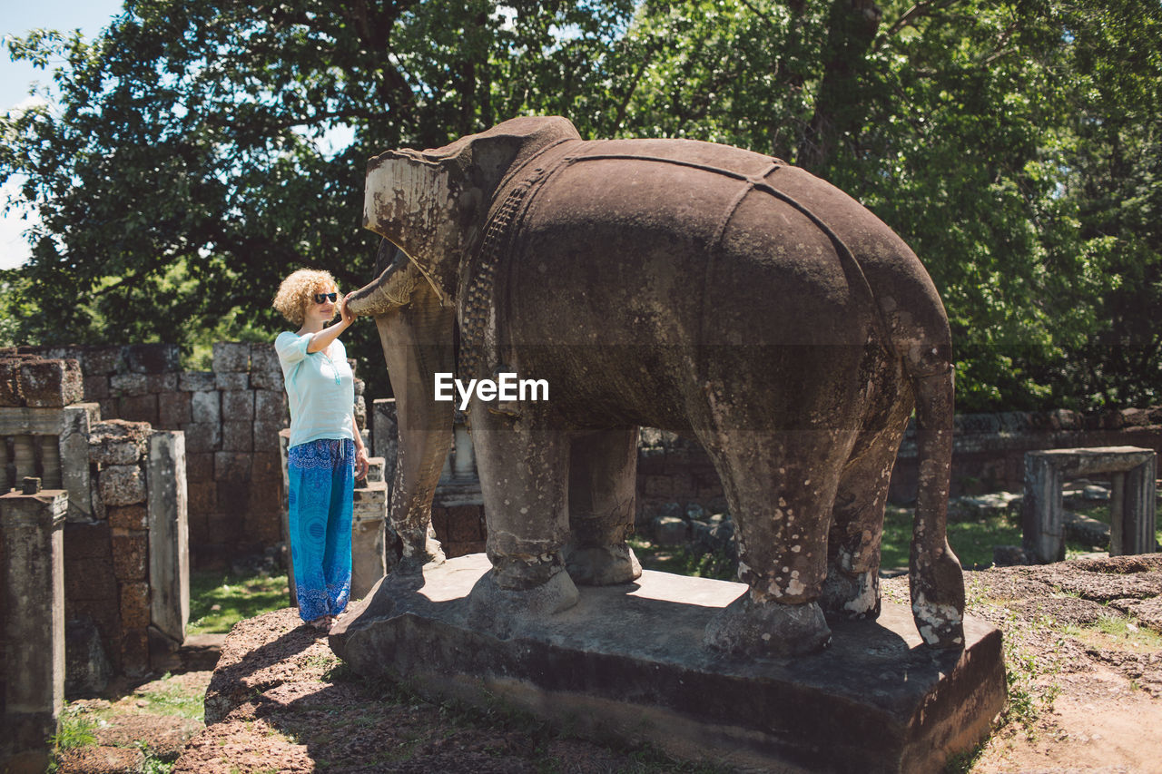 Woman looking at elephant statue against trees