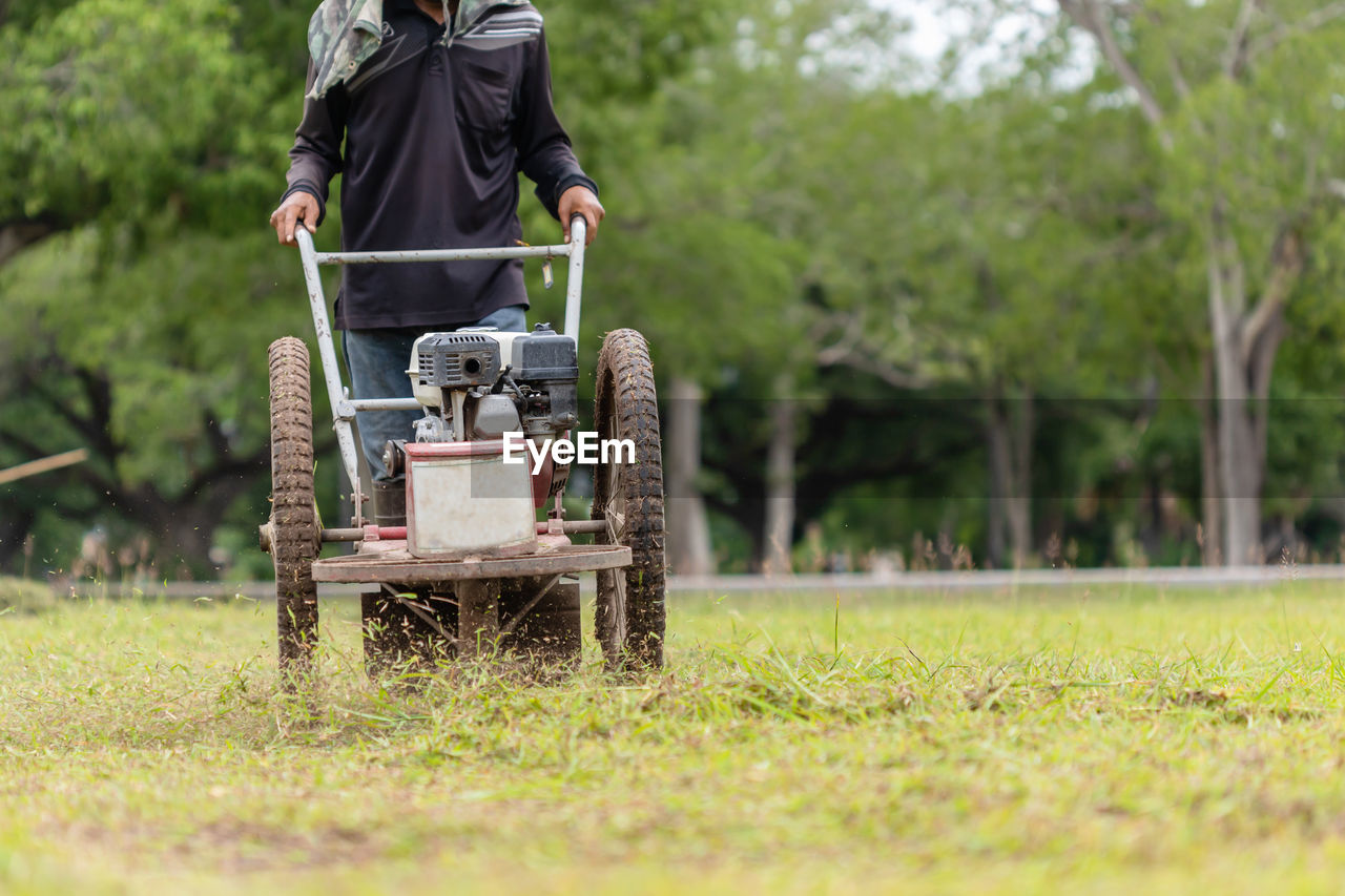 Thai worker mowing grass with machine in the public garden