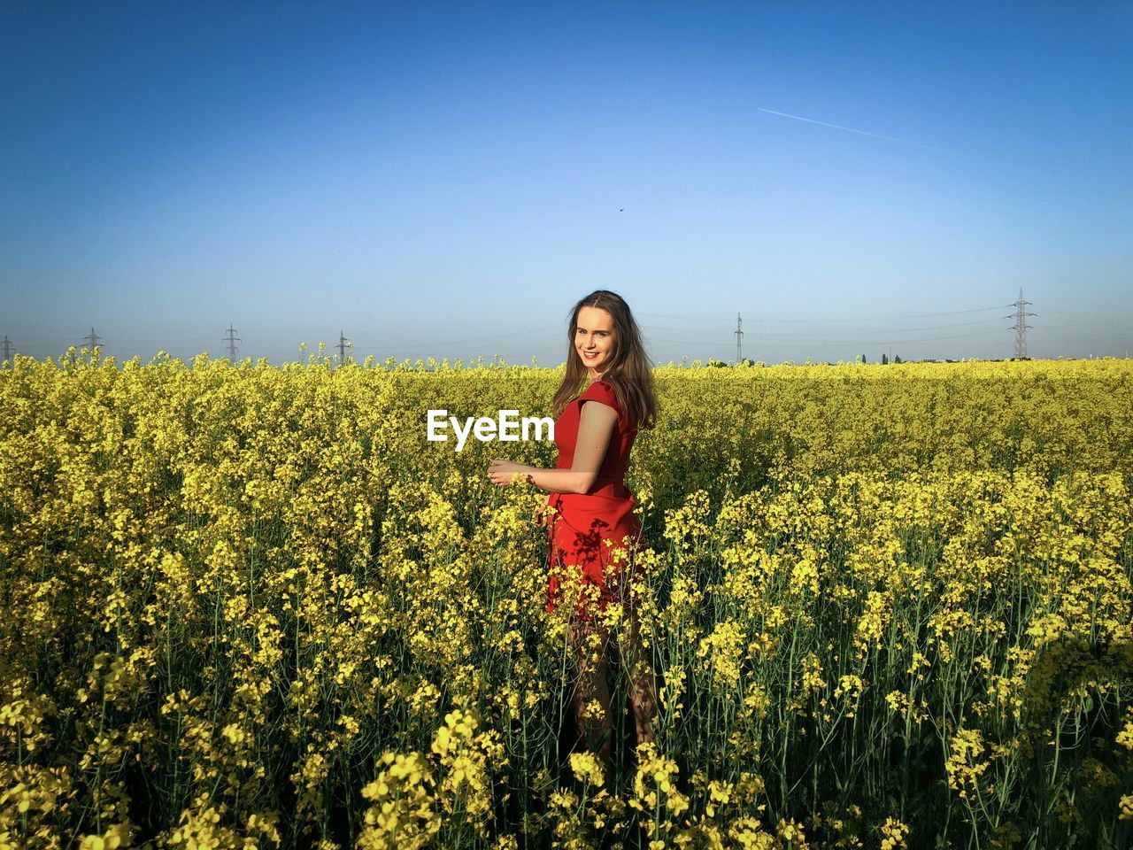 Woman in red dress in a field of canola flowers