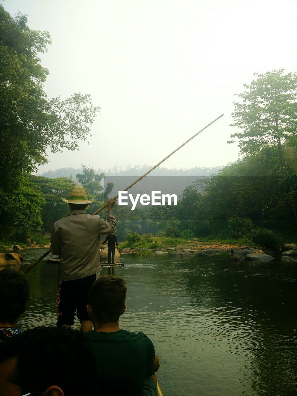 People on boat at river against clear sky