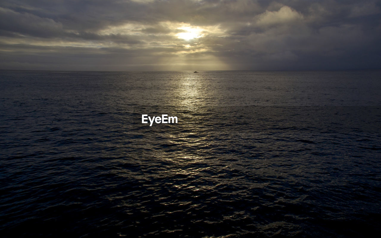 Scenic view of sea against cloudy sky during sunset