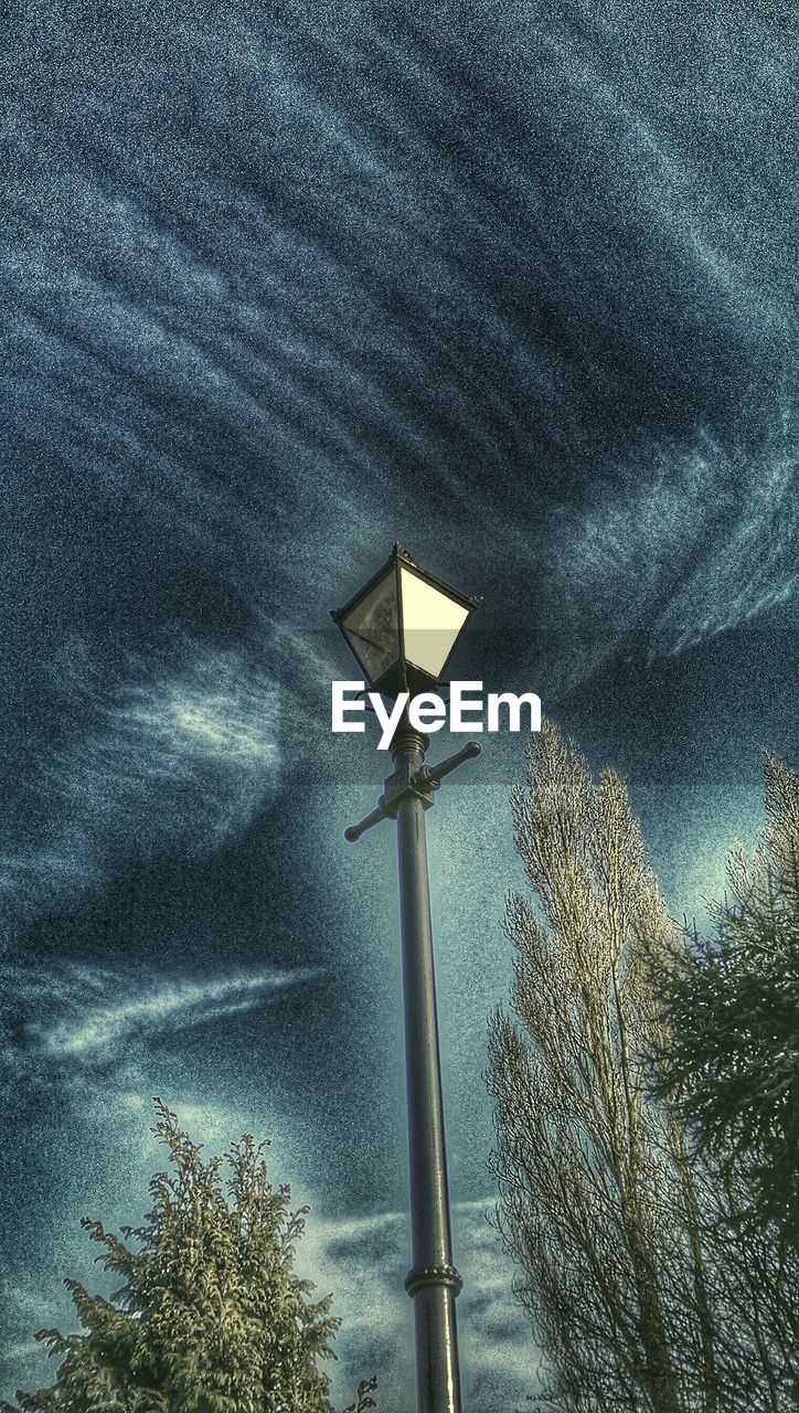 LOW ANGLE VIEW OF STREET LIGHTS AGAINST CLOUDY SKY