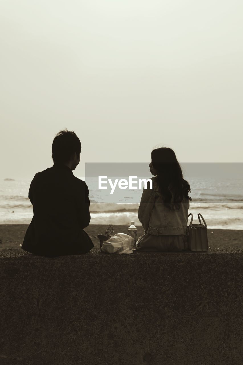 Rear view of couple overlooking calm sea