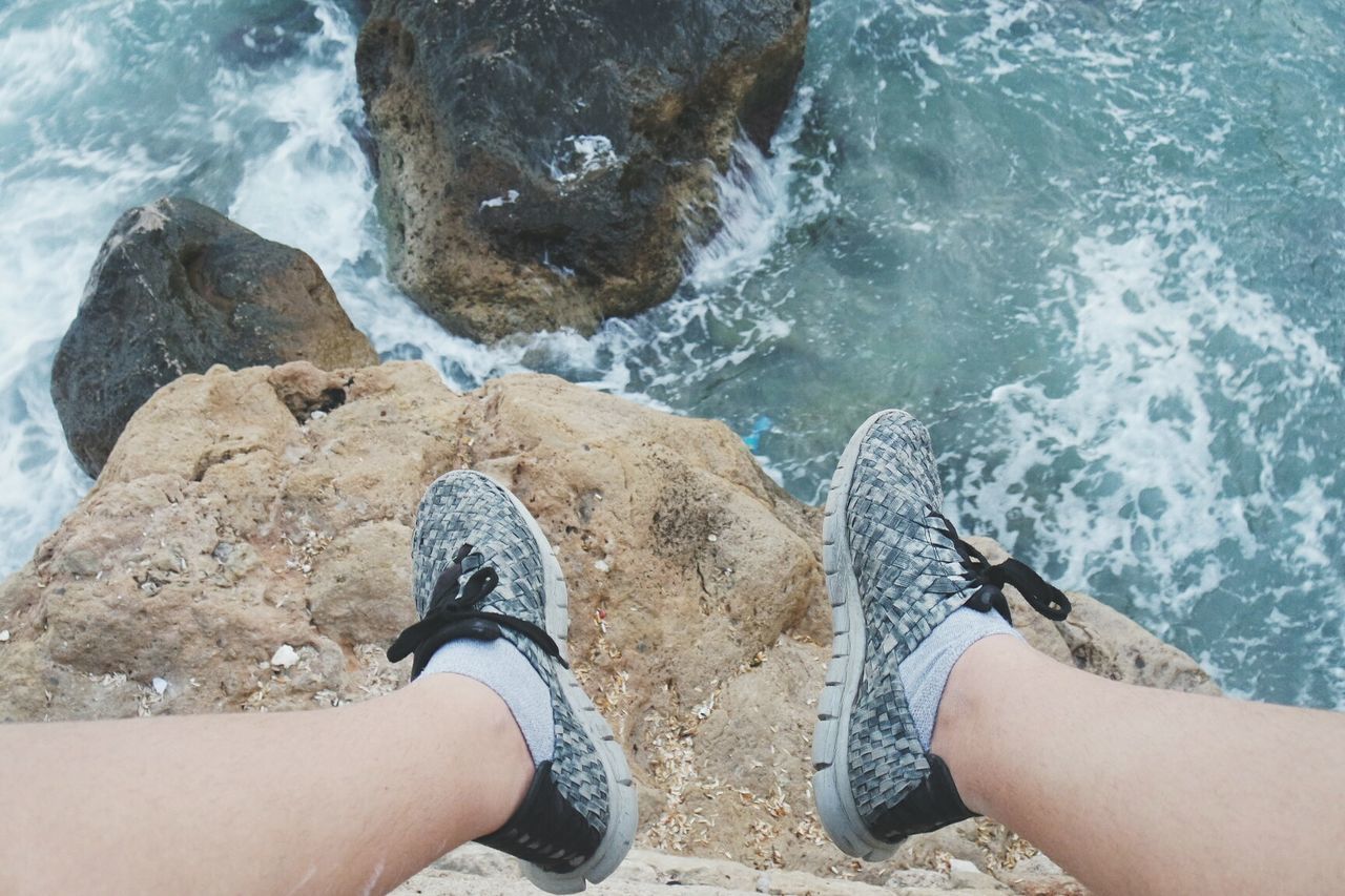 Low section of person sitting on rock overlooking river