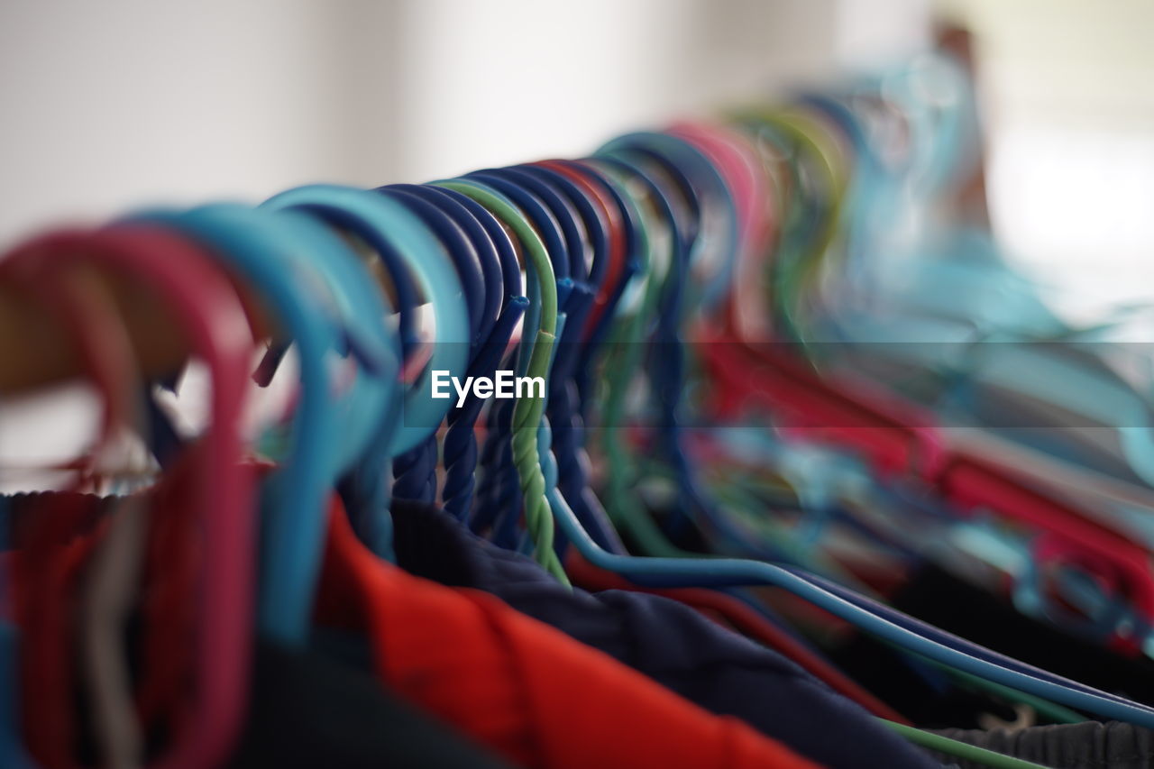 red, blue, multi colored, in a row, selective focus, variation, close-up, indoors, no people, clothing, rack, large group of objects, store, coathanger