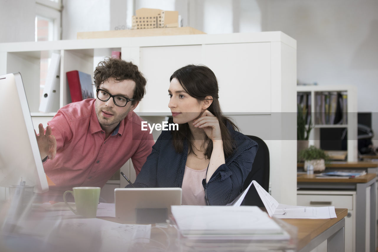 Man and woman discussing at desk in office