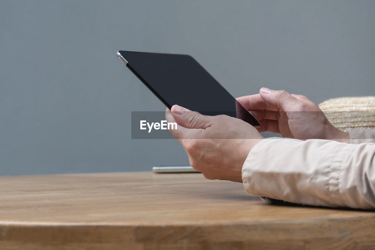 A woman is sitting at a table in a cafe with a tablet in her hands.