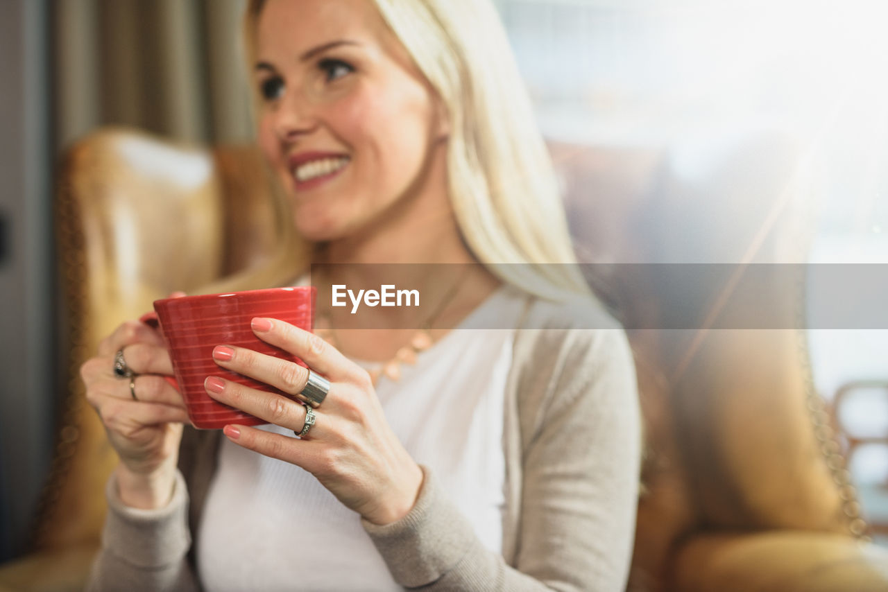 Cheerful female resting in armchair in cafe