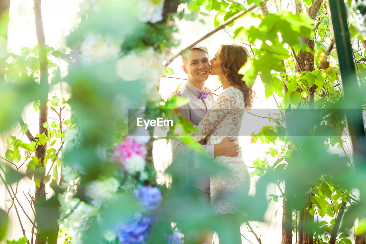 WOMAN AND WHITE FLOWERING PLANTS AGAINST WALL