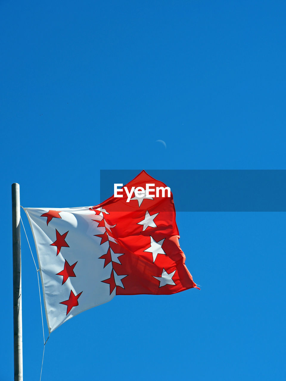 Low angle view of valais flag against clear blue sky